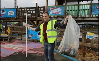 Employee holding up a bag of litter